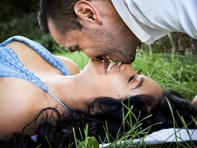 Um cara que pegou essas melhores dicas de primeiro encontro para homens beijando sua namorada na grama.