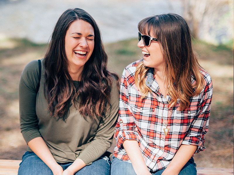 Dos mujeres discutiendo consejos sobre citas para mujeres de entre 20 y 30 años mientras se ríen juntas.
