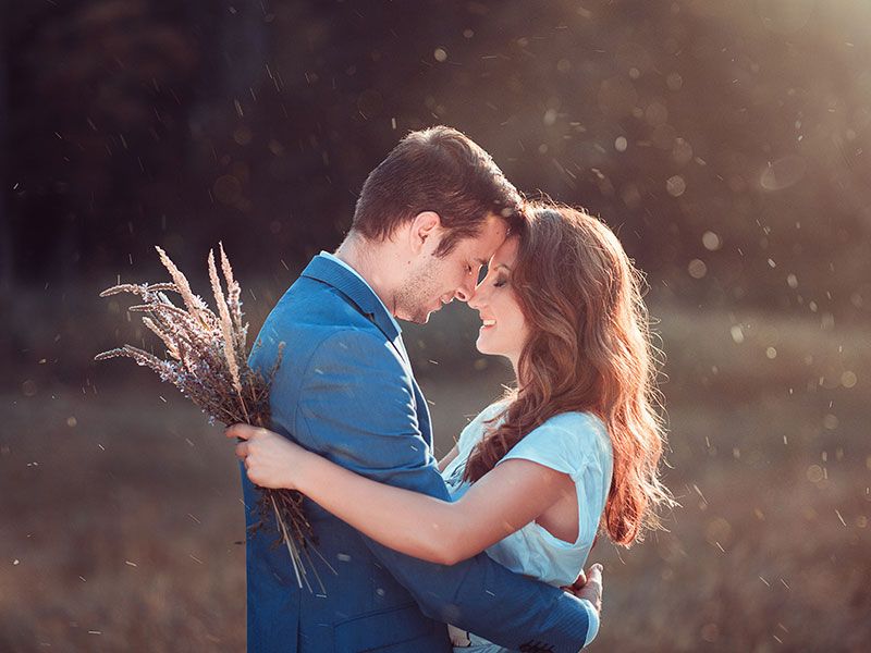 Um casal que sabe o que é romance, abraçando-se ao sol em um campo.