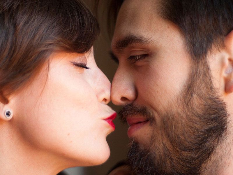 Um casal prestes a se beijar de olhos fechados, mostrando uma das diferentes maneiras de dizer eu te amo.