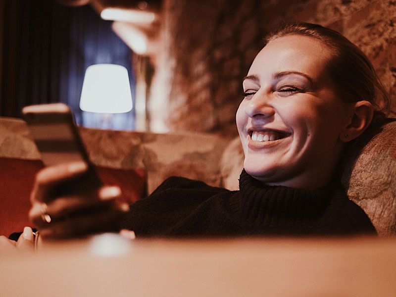 Una mujer de Tinder en la aplicación de citas Tinder riendo mientras