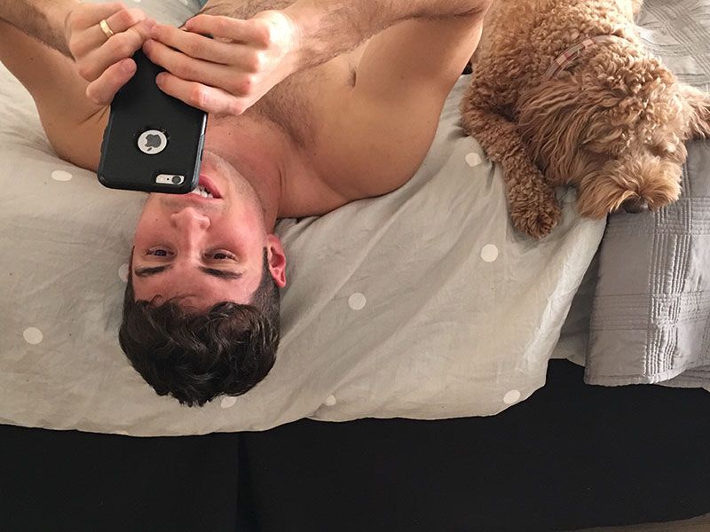 Puisis, rakstot Tinder ziņas, atrodoties gultā ar savu suni blakus.