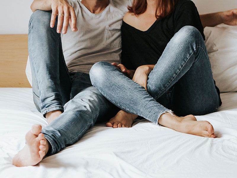 Una pareja sin confianza en su relación, sentados juntos en la cama conversando sobre ello.