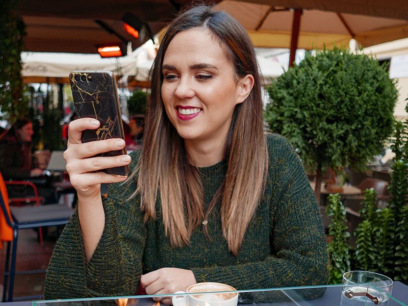 Uma mulher recebendo mensagens de texto fofas do cara de quem ela gosta e sorrindo enquanto ela
